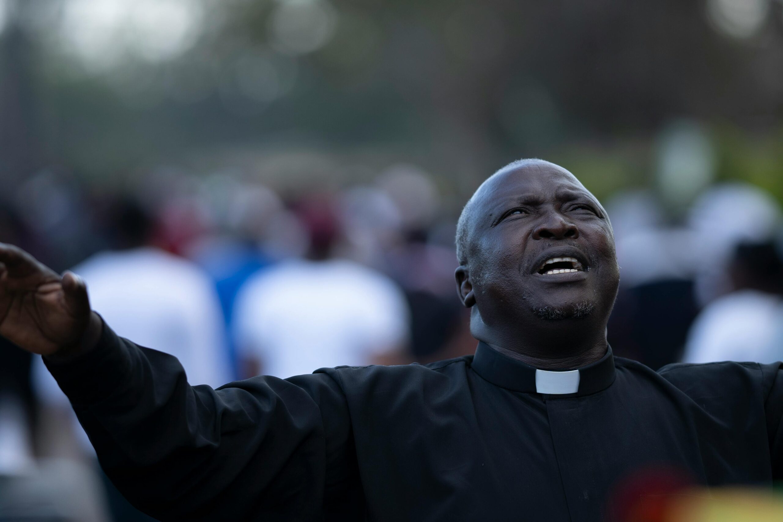 A passionate male priest sings with fervor, outdoors, enhancing spiritual experience.